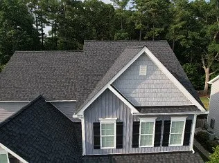 Aerial view of a residential home with a new dark shingle roof installed by Dubya Roofing and Gutters in South Carolina